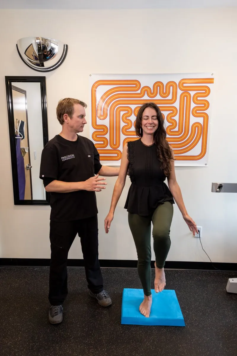 Patient performing cerebellar balance test on foam pad during functional cervical and neurological assessment at Precision Chiropractic in Vermont